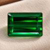Natural emerald cut green tourmaline gemstone on beige jewelry display