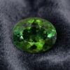 Natural oval green tourmaline gemstone on dark grey fabric
