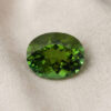 Natural oval green tourmaline gemstone on soft cream fabric