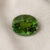 Natural oval green tourmaline gemstone on soft cream fabric