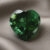 Natural heart shaped green tourmaline gemstone on soft grey fabric