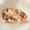 Natural Imperial Topaz pear cut gemstone on ivory fabric