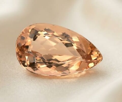 Natural Imperial Topaz pear cut gemstone on ivory fabric