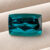 Natural Blue Tourmaline cushion cut gemstone on ivory fabric
