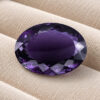 Natural Deep Purple Iolite oval cut gemstone on ivory fabric