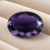 Natural Deep Purple Iolite oval cut gemstone on ivory fabric