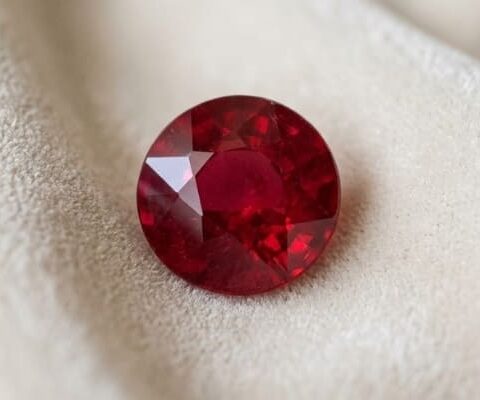 Natural Mozambique Ruby round cut red gemstone on ivory fabric