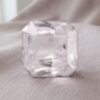 Natural emerald-cut light peach sapphire gemstone on soft fabric