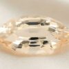 Natural marquise-cut golden peach sapphire gemstone on ivory fabric