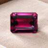 Natural Rhodolite Garnet gemstone with deep pinkish-red color and emerald cut, front view.