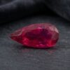 Natural Rubellite Tourmaline gemstone with rich raspberry-red color and pear cut, angled view.