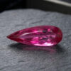 Natural Rubellite Tourmaline gemstone with vibrant raspberry-pink color and pear cut, angled view.