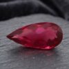 Natural Rubellite Tourmaline gemstone with rich raspberry-red color and pear cut, angled view.