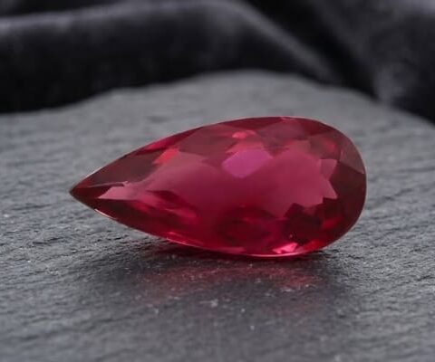 Natural Rubellite Tourmaline gemstone with rich raspberry-red color and pear cut, angled view.