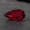 Natural Rubellite Tourmaline gemstone with deep ruby-red color and pear cut, angled view.