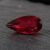 Natural Rubellite Tourmaline gemstone with deep ruby-red color and pear cut, angled view.