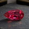Natural Rubellite Tourmaline gemstone with vibrant raspberry-red color and pear cut, angled view.