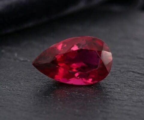 Natural Rubellite Tourmaline gemstone with deep raspberry-red color and pear cut, angled view.