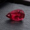 Natural Rubellite Tourmaline gemstone with deep raspberry-red color and pear cut, angled view.