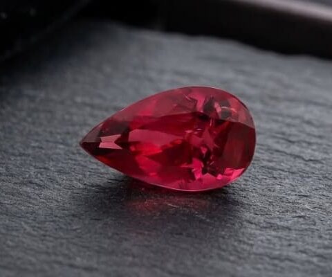 Natural Rubellite Tourmaline gemstone with deep raspberry-red color and pear cut, angled view.