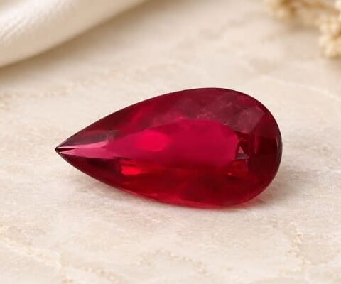 Natural Rubellite Tourmaline gemstone with vivid ruby-red color and pear cut, angled view.