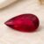 Natural Rubellite Tourmaline gemstone with vivid ruby-red color and pear cut, angled view.