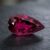 Natural Rubellite Tourmaline gemstone with deep raspberry-pink color and pear cut, angled view.
