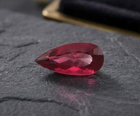 Natural Rubellite Tourmaline gemstone with rich raspberry-red color and pear cut, angled view.