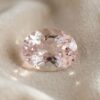 Natural oval soft pink morganite loose gemstone displayed on elegant satin fabric
